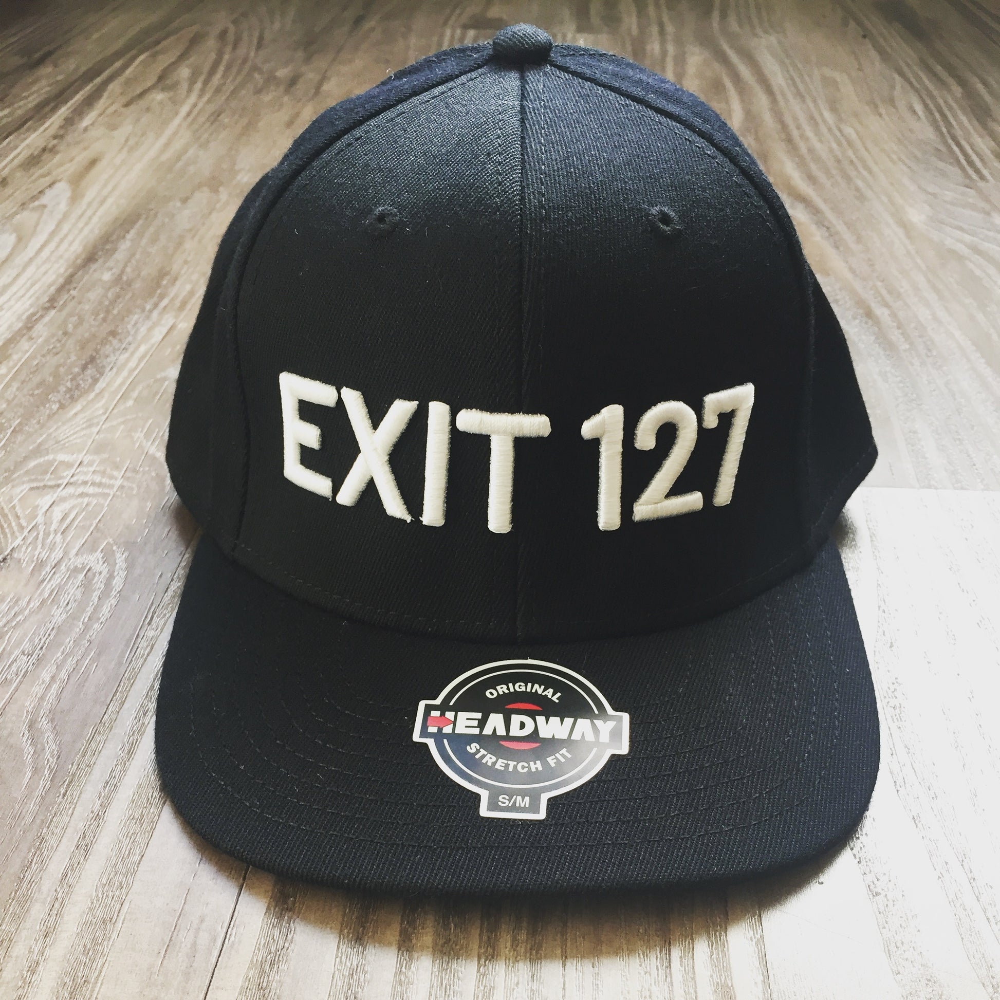 Black fitted cap with "EXIT 127" written on the front of the cap